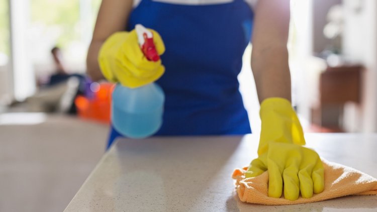 A close up of a professional house cleaner wiping a surface.